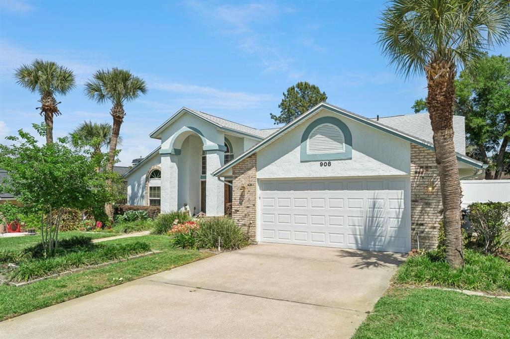 A single-story house with a white stucco facade, brick accents, and a two-car garage — 908 ALMOND TREE CIRCLE, ORLANDO, FL