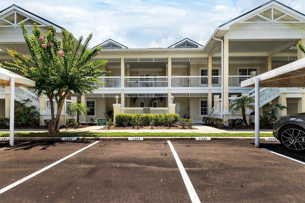A two-story apartment building with covered parking spaces in the foreground — 3706 54TH DRIVE W UNIT 102, BRADENTON, FL