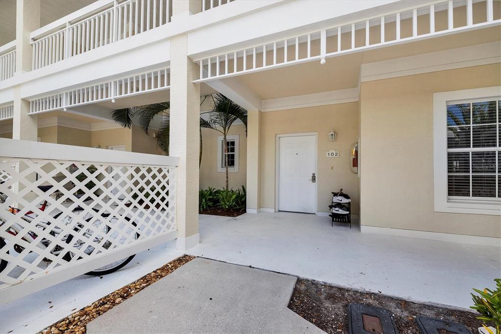 The exterior view shows a covered entryway with a white door labeled 102 — 3706 54TH DRIVE W UNIT 102, BRADENTON, FL