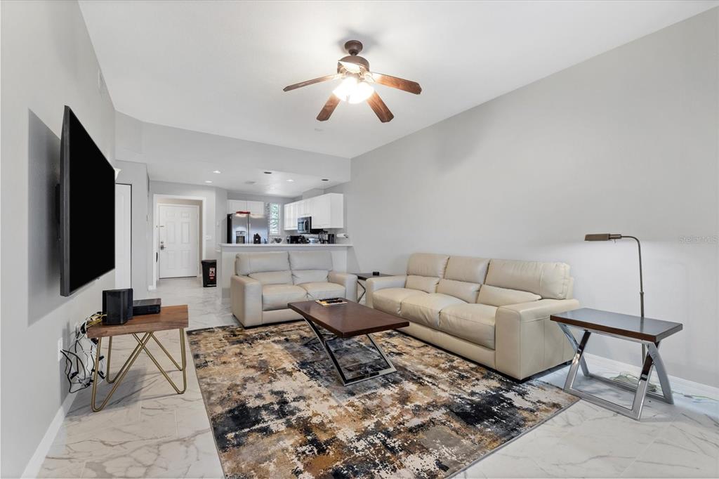 A living room features light tile floors, a patterned area rug, and two beige sofas — 3706 54TH DRIVE W UNIT 102, BRADENTON, FL