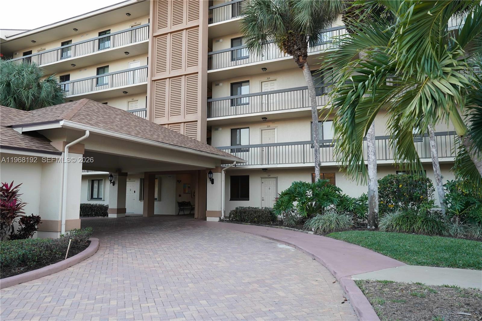 A multi-story apartment building features a covered driveway entrance and balconies with metal railings — 2101 Marina Isle Way # 104, Jupiter FL 33477, JUPITER, FL
