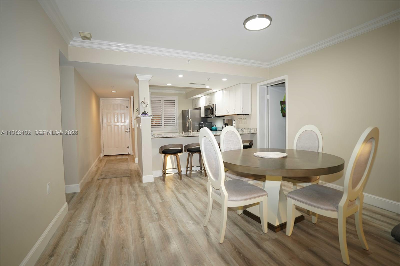 A dining area with a round table and chairs sits adjacent to an open kitchen — 2101 Marina Isle Way # 104, Jupiter FL 33477, JUPITER, FL