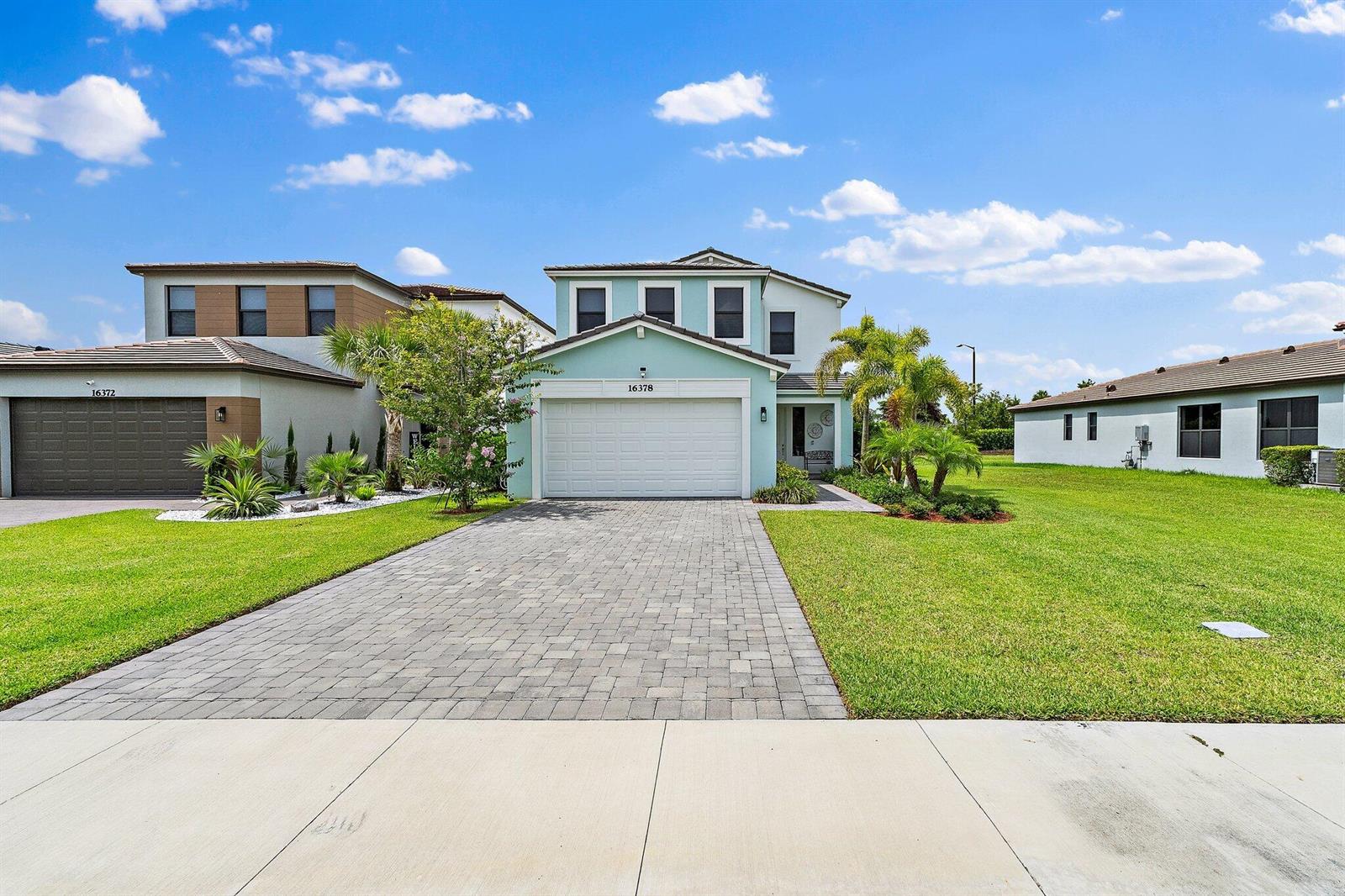 A light green two-story house with a paved driveway and a two-car garage — 16378 Sea Turtle Place, Westlake FL 33470, WESTLAKE, FL