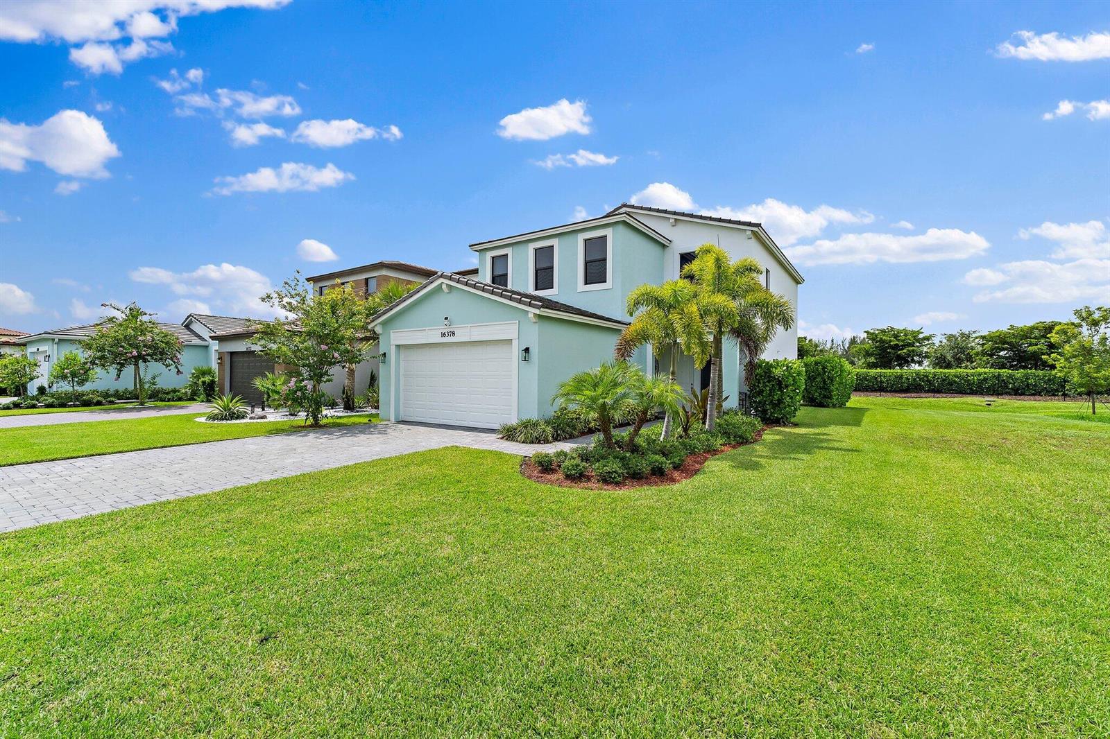 A two-story light green house with a two-car garage and a large front lawn — 16378 Sea Turtle Place, Westlake FL 33470, WESTLAKE, FL