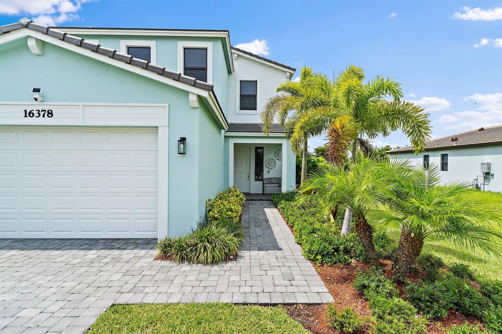 A two-story house with light green siding, a paved walkway, and palm trees — 16378 Sea Turtle Place, Westlake FL 33470, WESTLAKE, FL