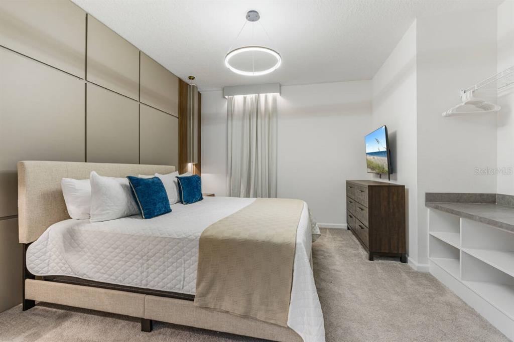 A bedroom features a king bed, a dark wood dresser, and a built-in shelving unit — 5943 HIGH SEAS DRIVE, ORLANDO, FL