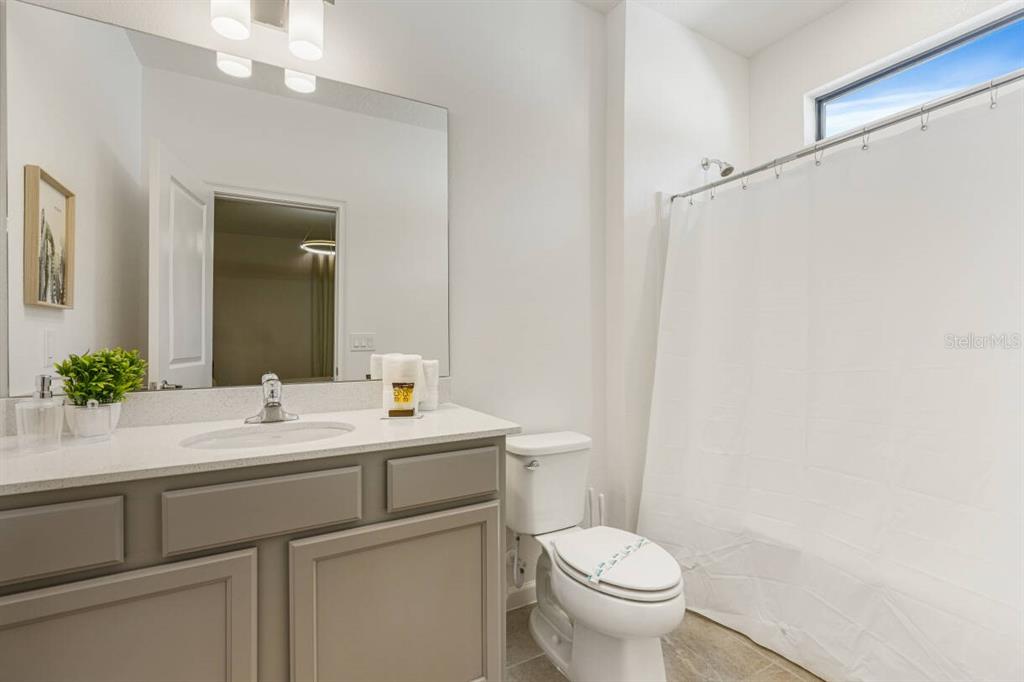 A bathroom features a gray vanity with a white countertop, a toilet, and a shower curtain — 5943 HIGH SEAS DRIVE, ORLANDO, FL