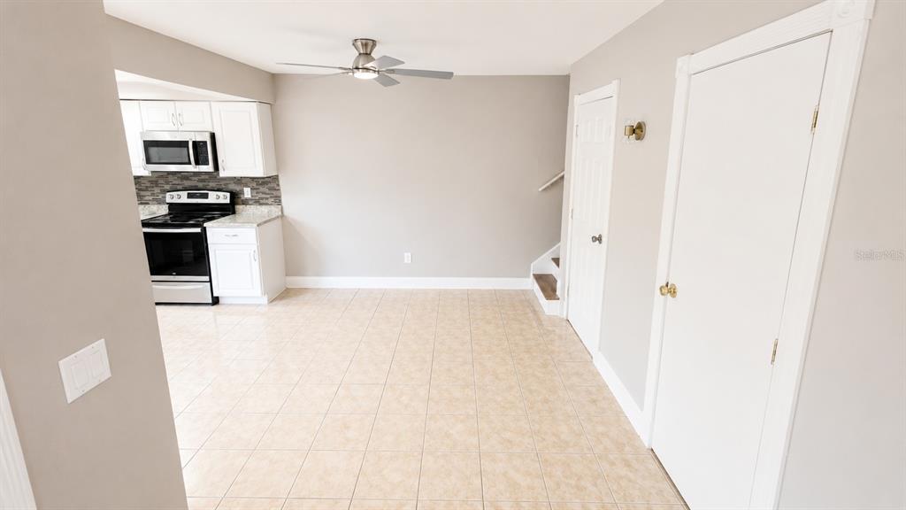 A kitchen with white cabinets and stainless steel appliances opens into a tiled dining area — 120 MOONSTONE COURT, PORT ORANGE, FL
