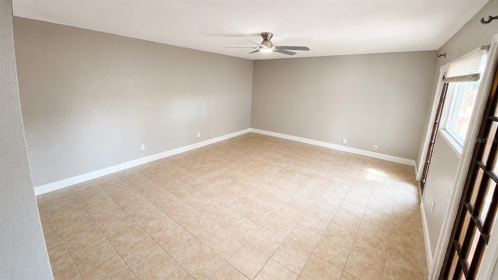 An empty room features beige tile flooring, light gray walls, and a ceiling fan — 120 MOONSTONE COURT, PORT ORANGE, FL