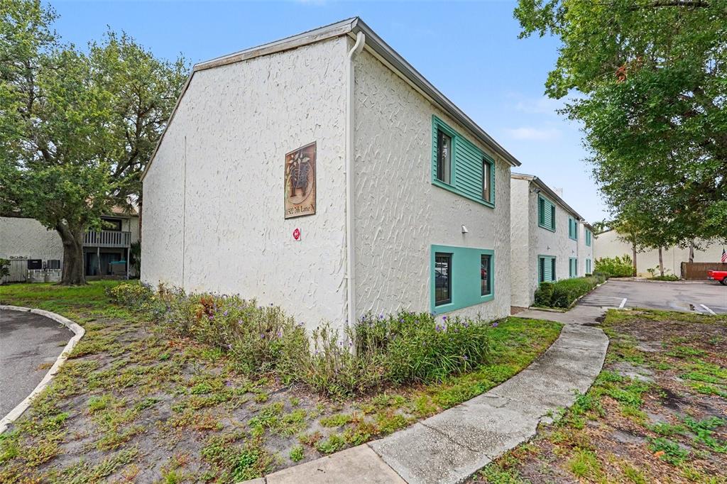 The exterior of a two-story stucco apartment building features teal accents and a staircase — 11502 7TH LANE N UNIT 1401, ST PETERSBURG, FL