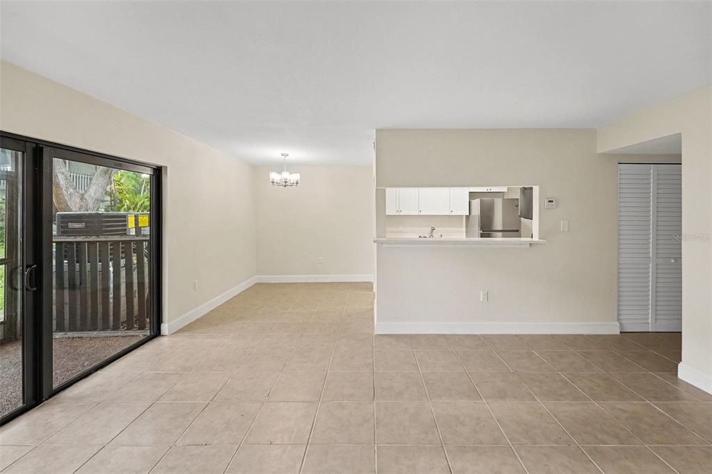 An open-concept living and dining area features beige tile flooring and a kitchen pass-through window — 11502 7TH LANE N UNIT 1401, ST PETERSBURG, FL