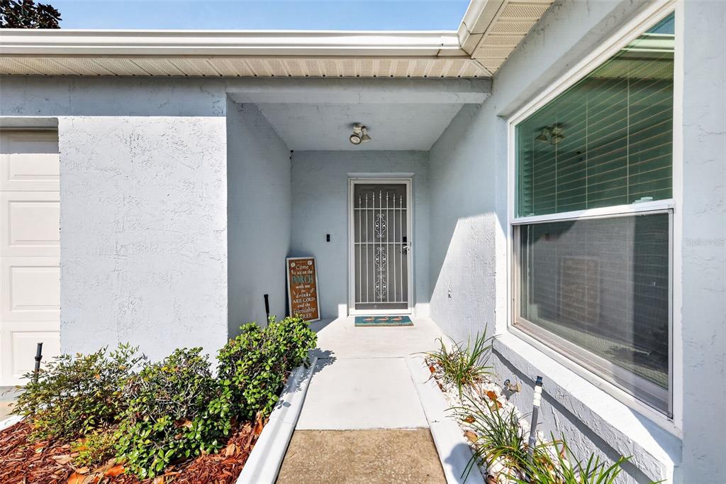 A concrete walkway leads to the front entrance of a house with a screen door — 1717 FRANCISCO STREET, THE VILLAGES, FL