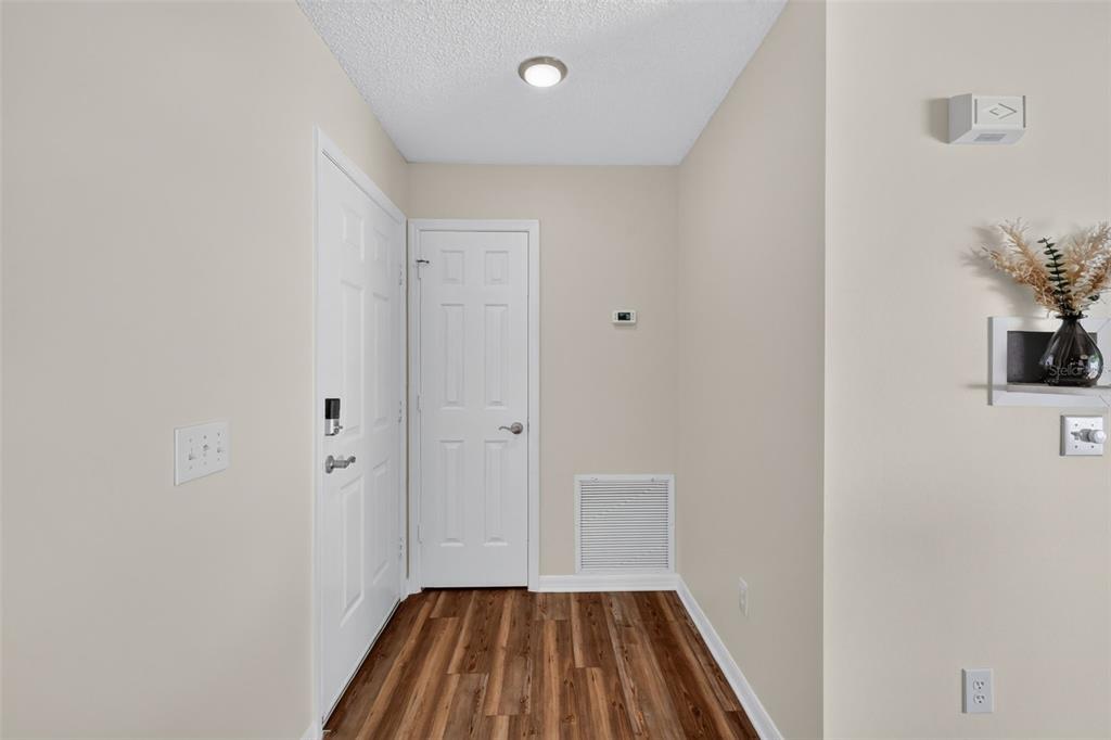 An entryway with wood-look flooring, two white doors, a ceiling light, and beige walls — 1717 FRANCISCO STREET, THE VILLAGES, FL