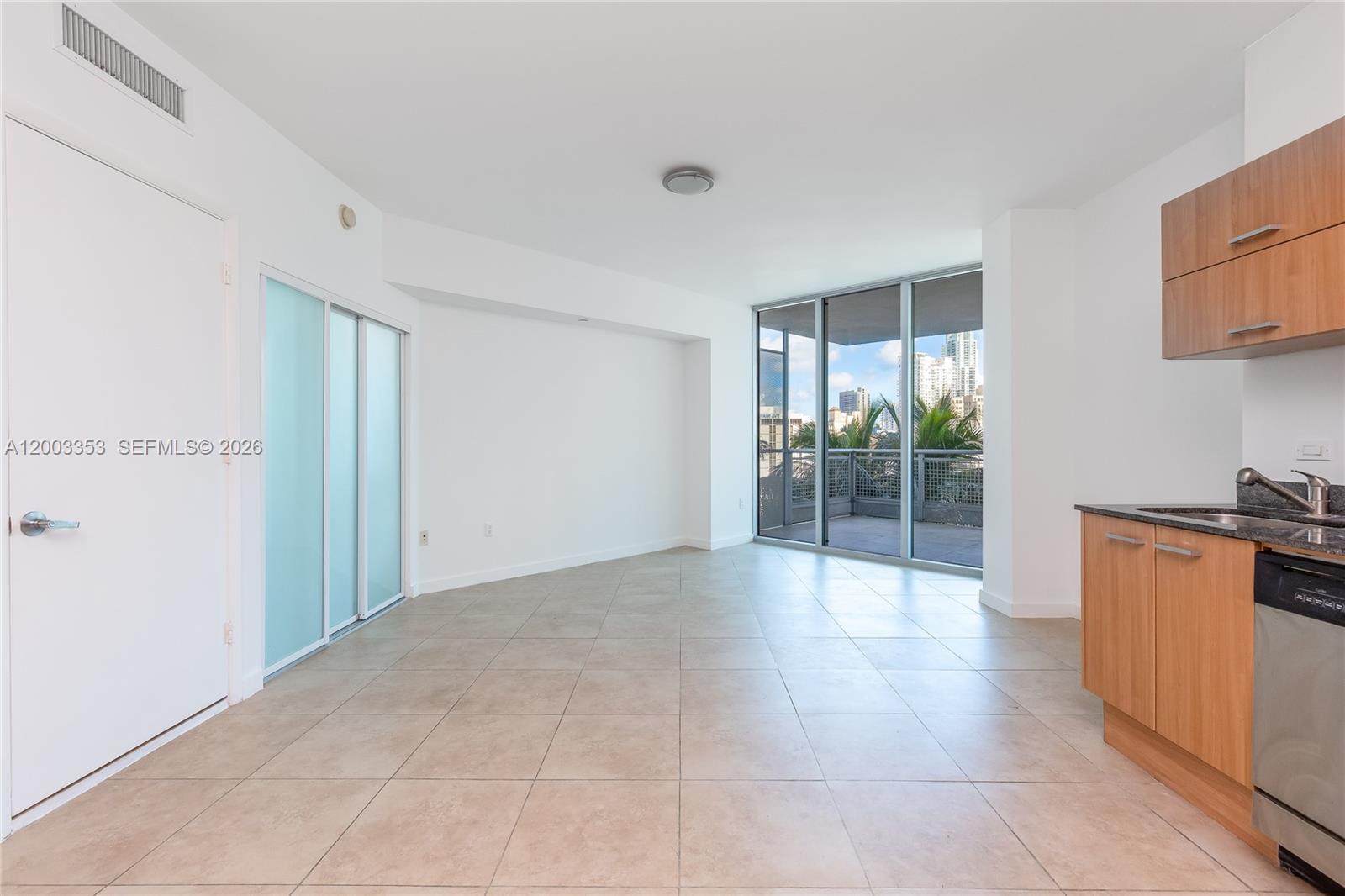 A bright living area with tile floors, a small kitchen, and a balcony with city views — 350 S Miami Ave # 1207, Miami FL 33130, MIAMI, FL