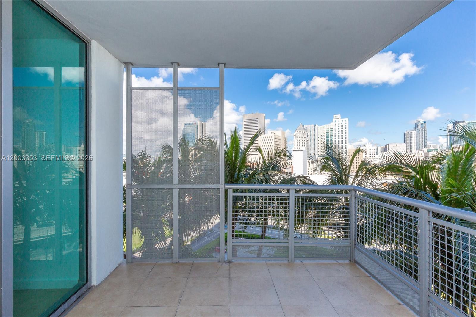 A balcony with tiled flooring, metal railings, and a view of a city skyline — 350 S Miami Ave # 1207, Miami FL 33130, MIAMI, FL