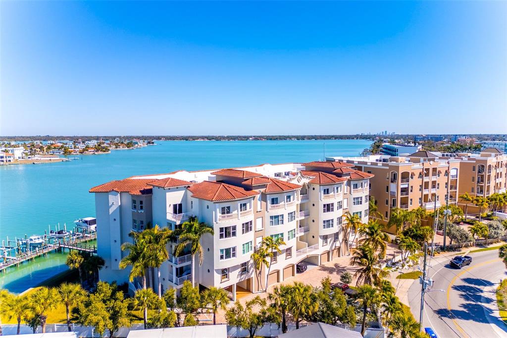 An aerial view shows a multi-story waterfront apartment complex with a tiled roof — 220 108TH AVENUE UNIT 304, TREASURE ISLAND, FL