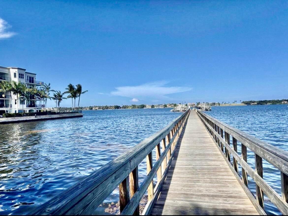 A long wooden pier extends over calm blue water toward a distant shoreline and buildings — 621 Windward Circle S, Boynton Beach FL 33435, BOYNTON BEACH, FL