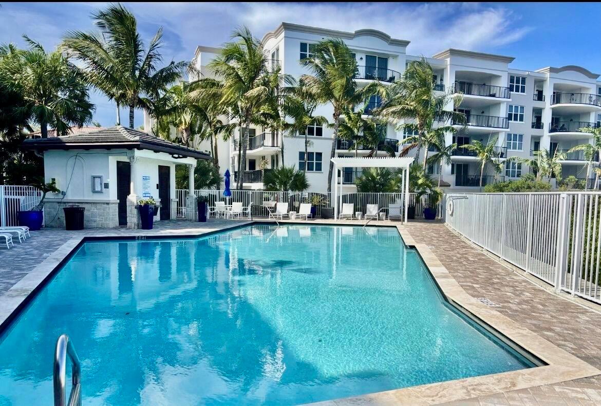 A swimming pool sits in front of a multi-story apartment building with palm trees — 621 Windward Circle S, Boynton Beach FL 33435, BOYNTON BEACH, FL