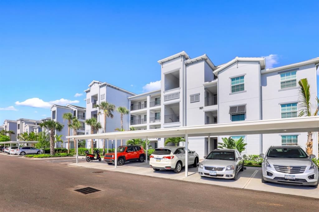 A multi-story apartment building with covered parking spaces and several parked vehicles in front — 14071 HERITAGE LANDING BOULEVARD UNIT 325, PUNTA GORDA, FL