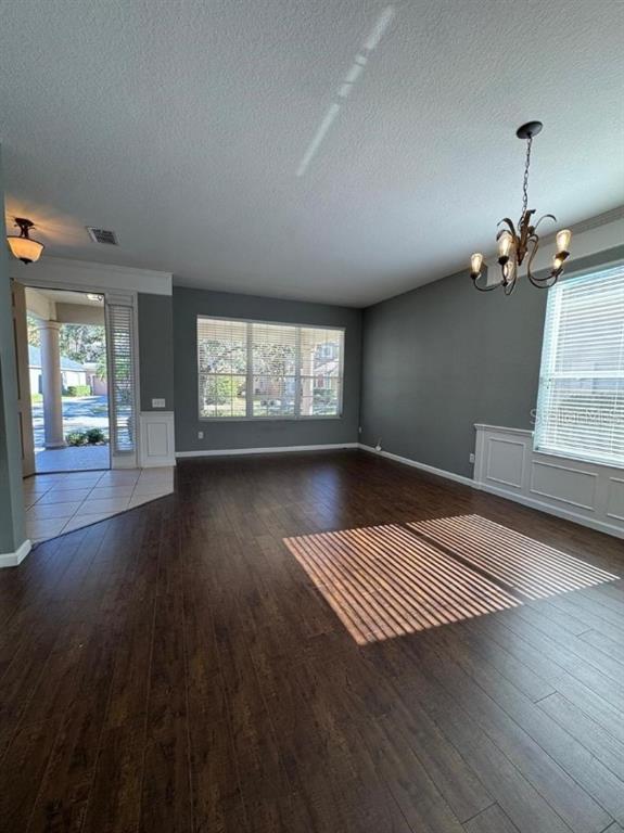 A dining room features dark wood flooring, gray walls, wainscoting, and a decorative chandelier — 8526 GREENBANK BOULEVARD, WINDERMERE, FL