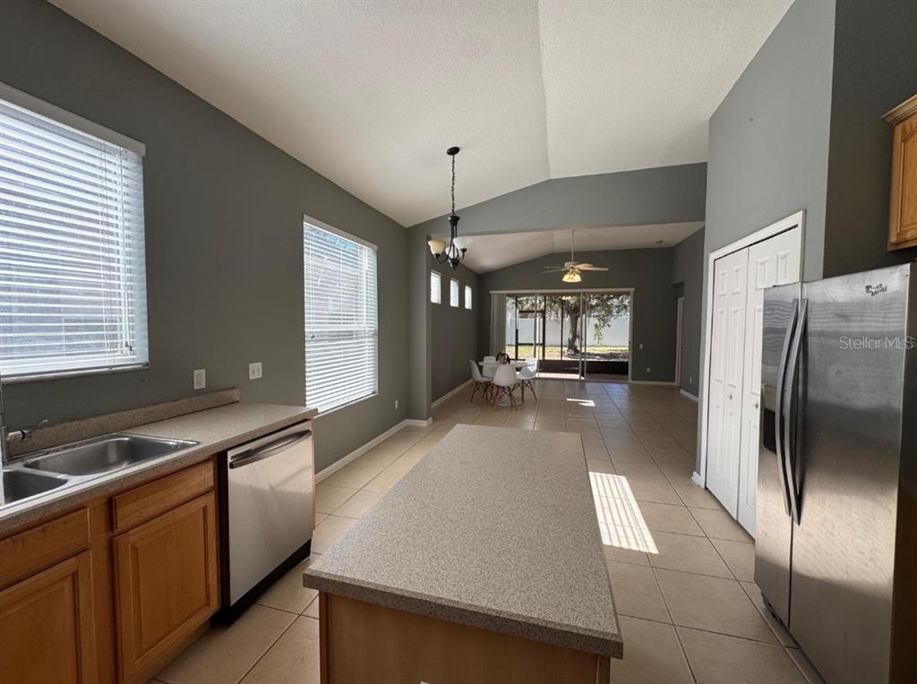 A kitchen with wood cabinets, a central island, and a view into the dining area — 8526 GREENBANK BOULEVARD, WINDERMERE, FL