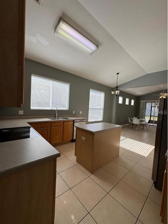 A kitchen with wood cabinets, a center island, and tile flooring opens to a dining area — 8526 GREENBANK BOULEVARD, WINDERMERE, FL