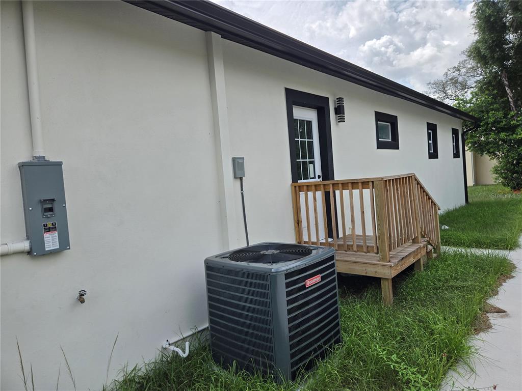 An exterior view of a house wall with an HVAC unit and a wooden deck — 701 E LINEBAUGH AVENUE, TAMPA, FL