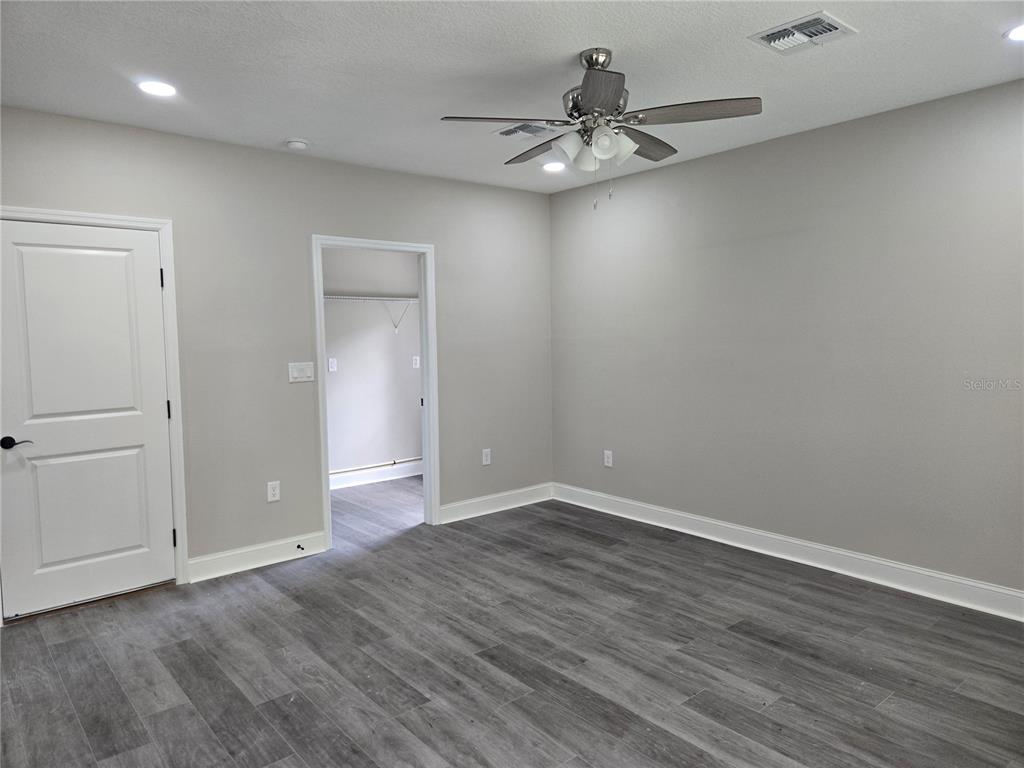 An empty bedroom features gray walls, wood-look flooring, a ceiling fan, and a walk-in closet — 701 E LINEBAUGH AVENUE, TAMPA, FL