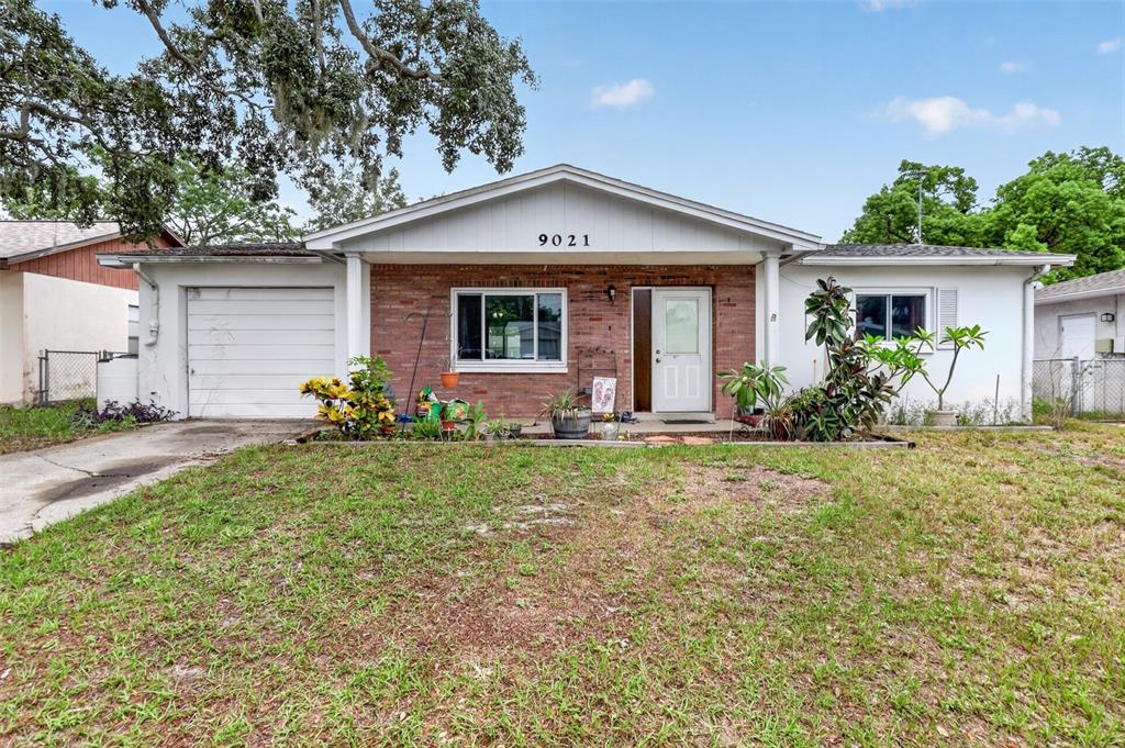 A single-story house with a brick facade, white siding, a garage, and a front lawn — 9021 RICHWOOD LANE, PORT RICHEY, FL