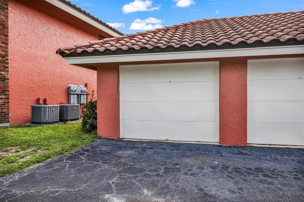 An exterior view of a stucco garage with a tiled roof and asphalt driveway — 3013 CLARK ROAD UNIT 6, SARASOTA, FL