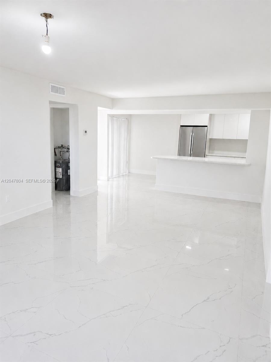 A bright, open-concept living area features white marble-look tile flooring and a kitchen breakfast bar — 479 NE 210th Cir Ter # 28, Miami FL 33179, MIAMI, FL