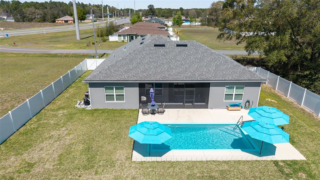 An aerial view of a house backyard featuring a swimming pool and two blue umbrellas — 4838 SW 130TH STREET, OCALA, FL