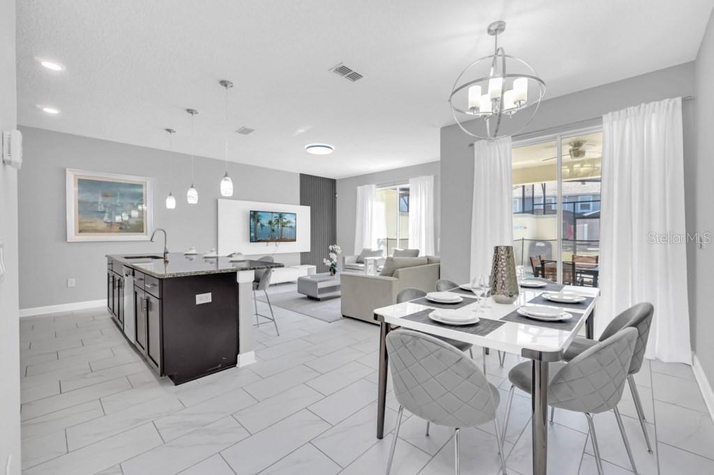 An open-concept kitchen, dining area, and living room feature white tile floors and modern decor — 4876 ROMEO CIRCLE, KISSIMMEE, FL