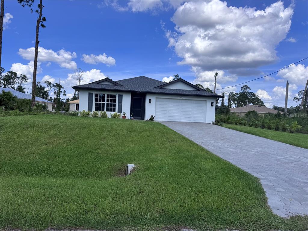 A white single-story house with a dark roof and a paved driveway under a blue sky — 2362 HAGOPLAN LANE, NORTH PORT, FL