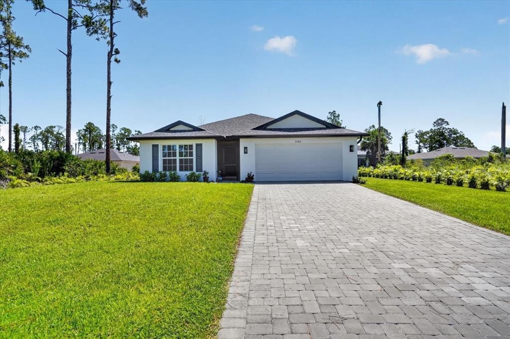 A single-story house with a white exterior, a paved driveway, and a two-car garage — 2362 HAGOPLAN LANE, NORTH PORT, FL