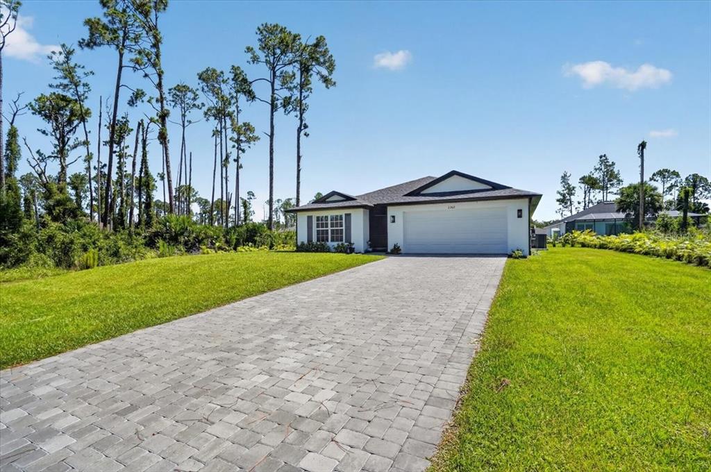 A single-story house with a paved driveway and a two-car garage sits on a lawn — 2362 HAGOPLAN LANE, NORTH PORT, FL