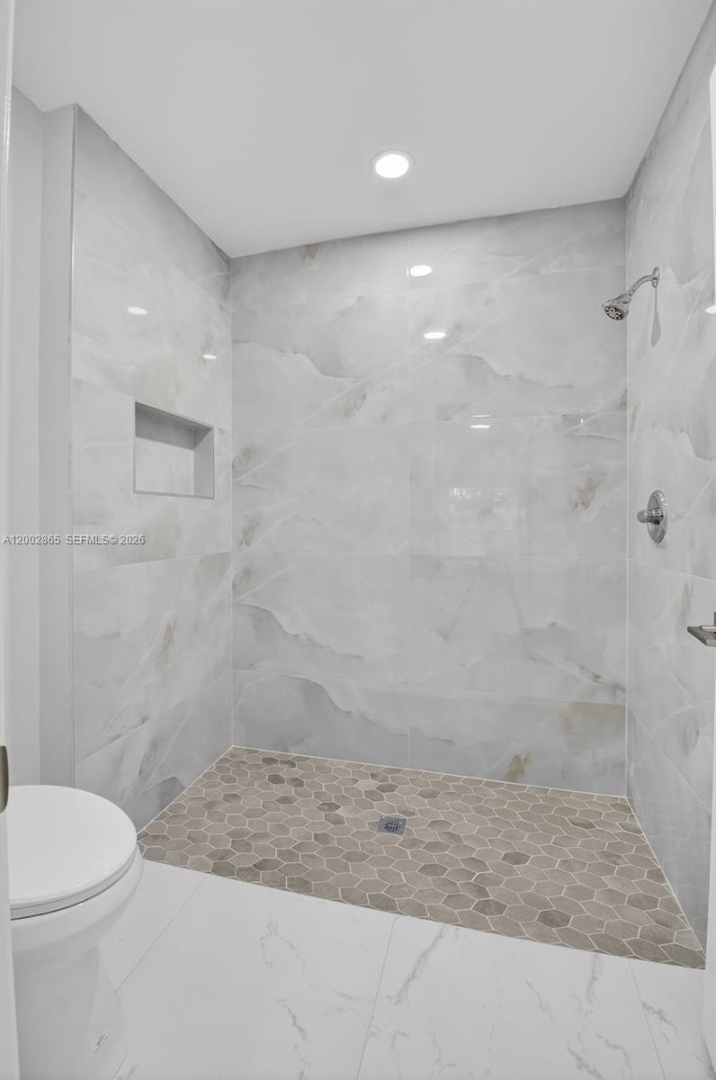 A bathroom features a walk-in shower with light marble-look tiles and a hexagonal tile floor — 8067 Summerbreeze Ln, Boca Raton FL 33496, BOCA RATON, FL