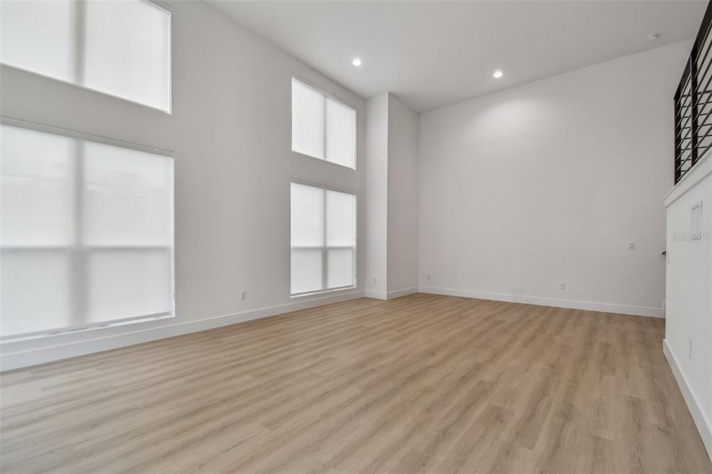 An empty room with high ceilings, large windows, and light wood-look flooring — 3826 POMPANO DRIVE SE, ST PETERSBURG, FL