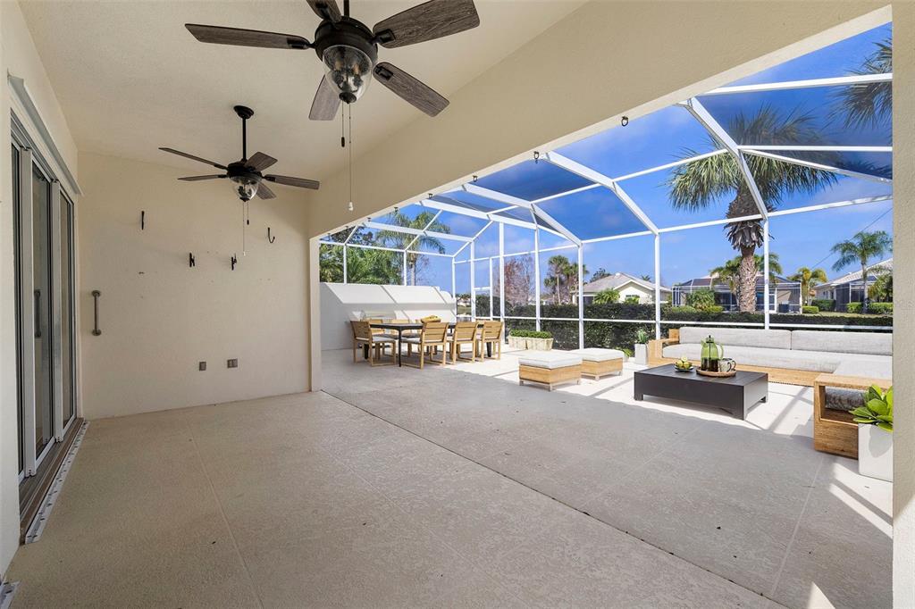A covered patio features two ceiling fans, a dining set, and a screened-in pool area — 5779 WILENA PLACE, SARASOTA, FL