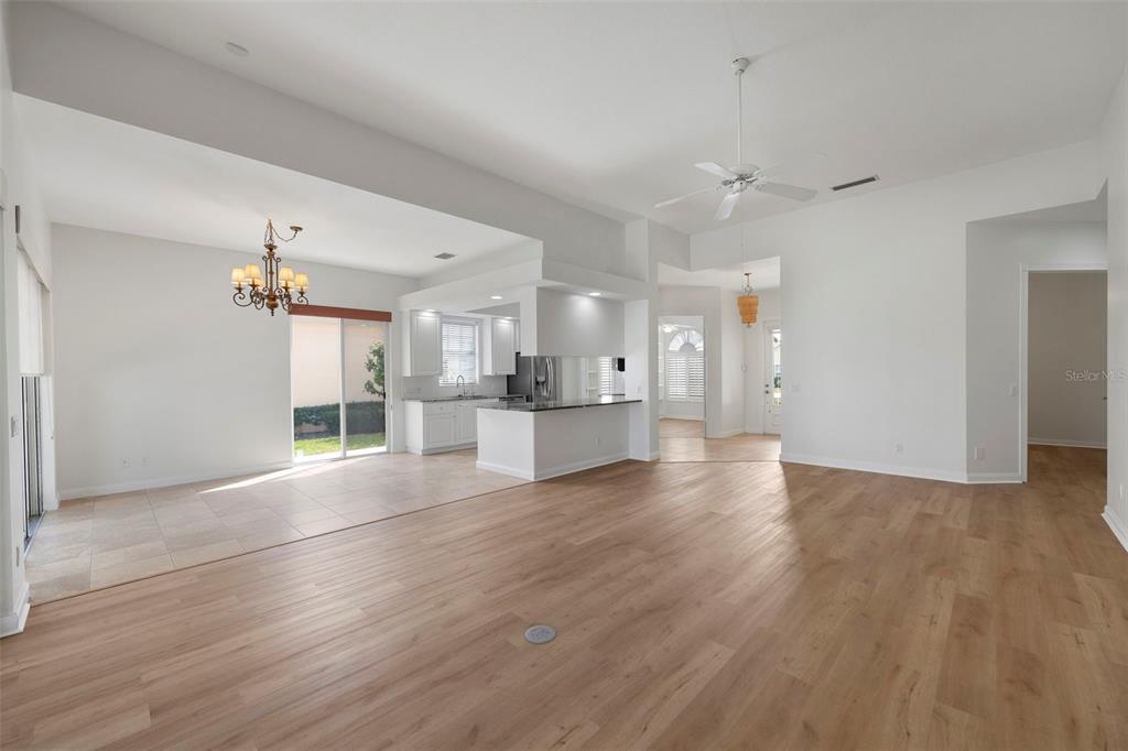 An open-concept living area features light wood-look flooring, a tiled dining space, and a kitchen — 5779 WILENA PLACE, SARASOTA, FL