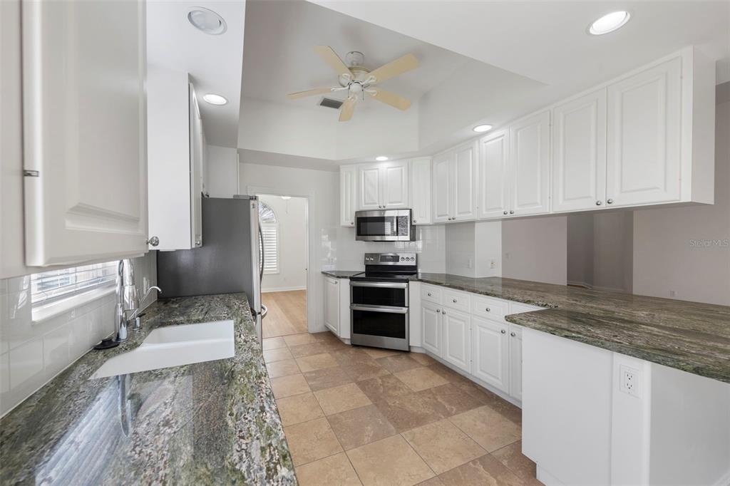 A kitchen with white cabinets, granite countertops, stainless steel appliances, and tile flooring — 5779 WILENA PLACE, SARASOTA, FL