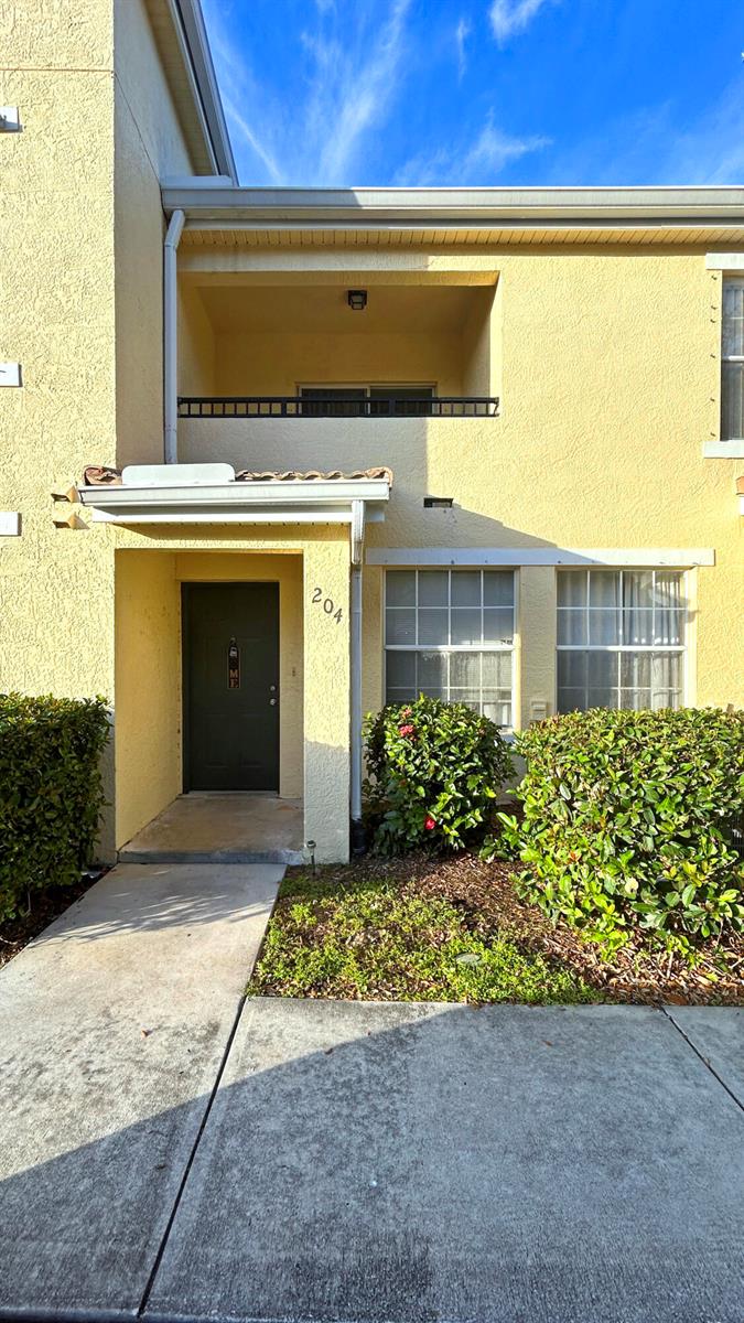 A yellow two-story building features a dark front door marked 204 and a small balcony — 104 SW Peacock Boulevard # 204, FL 34986, FL