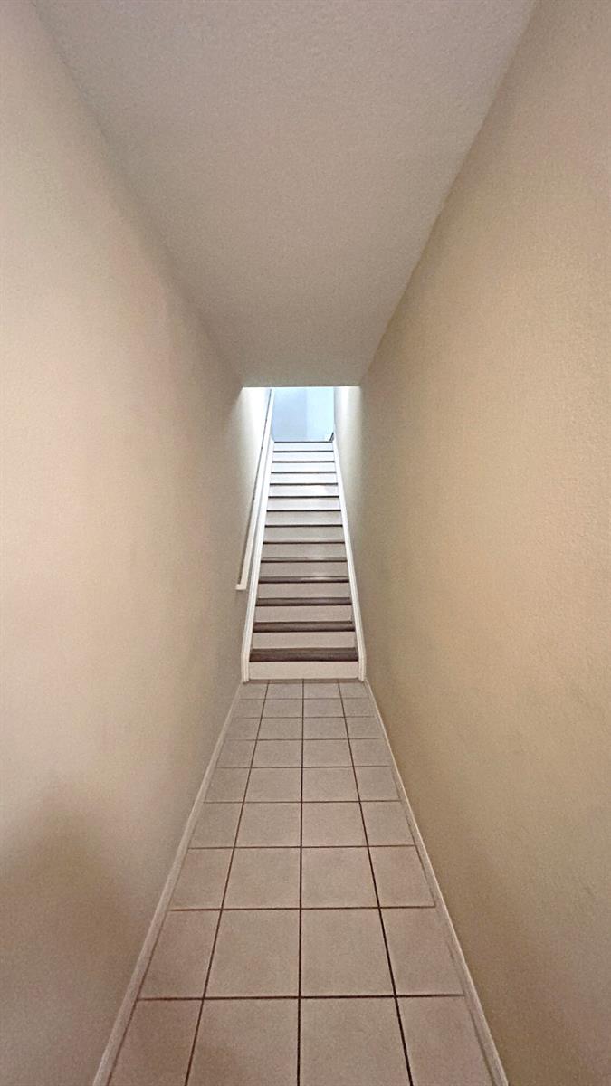 A tiled hallway leads to a staircase with white railings and carpeted steps — 104 SW Peacock Boulevard # 204, FL 34986, FL