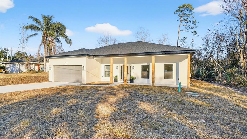 A single-story house with a garage, white stucco walls, and wooden porch support beams — 257 LAGO VISTA STREET, DEBARY, FL