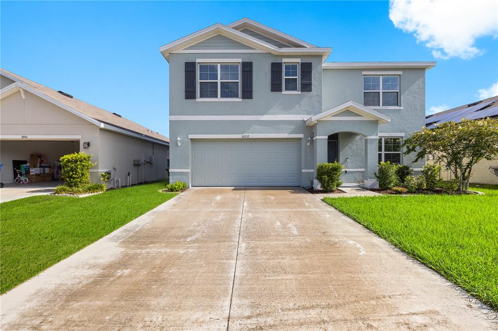 A two-story light blue house with a two-car garage and a concrete driveway — 10212 GOLDEN LIGHT COURT, RIVERVIEW, FL