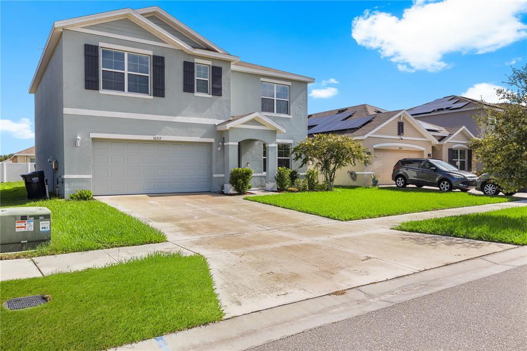 A two-story suburban house with a light blue exterior, a two-car garage, and a driveway — 10212 GOLDEN LIGHT COURT, RIVERVIEW, FL