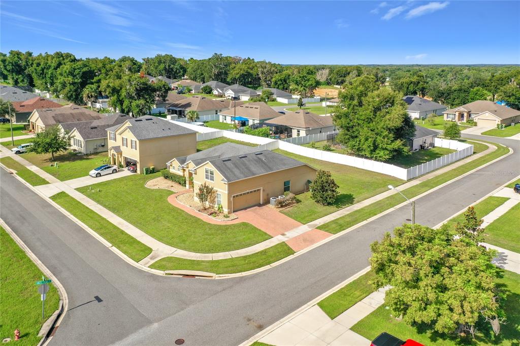 An aerial view of a suburban neighborhood featuring single-family homes on a corner lot — 301 ASHTON WOODS LANE, LEESBURG, FL