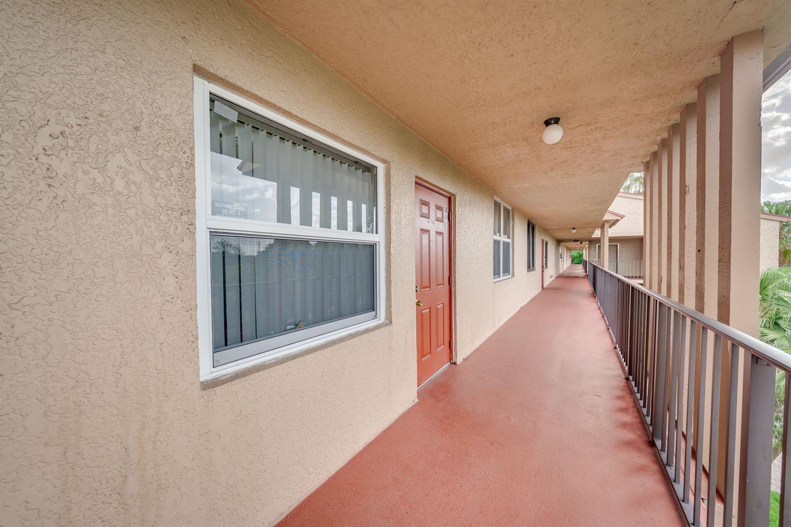 An exterior walkway with a red door, a window, and a metal railing — 7301 NW 1st Street # 402, Margate FL 33063, MARGATE, FL