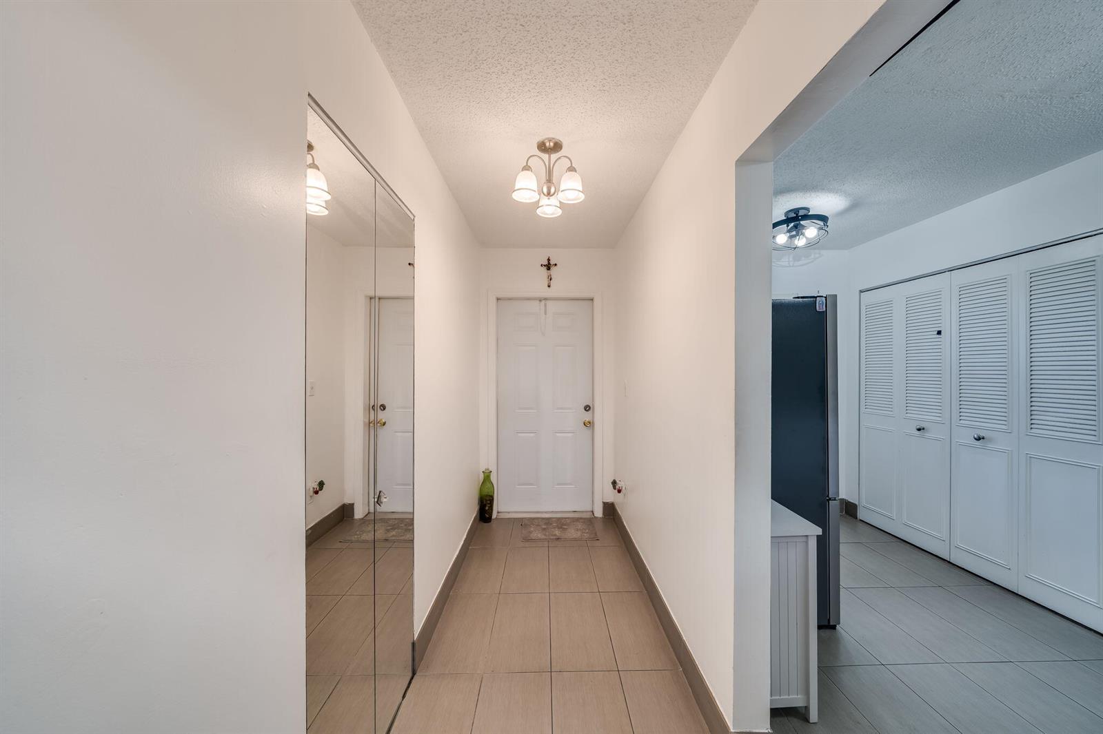 A tiled entryway leads to a white front door with a mirrored closet on the left — 7301 NW 1st Street # 402, Margate FL 33063, MARGATE, FL