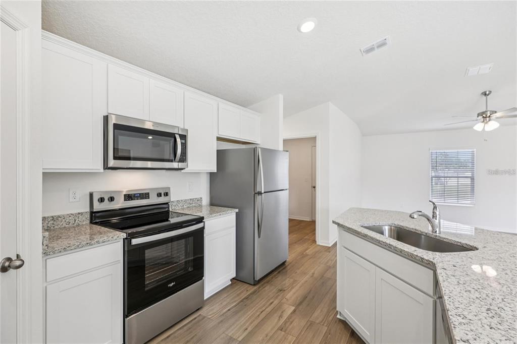 A kitchen with white cabinets, stainless steel appliances, and granite countertops — 16984 SW 40 CIRCLE, OCALA, FL